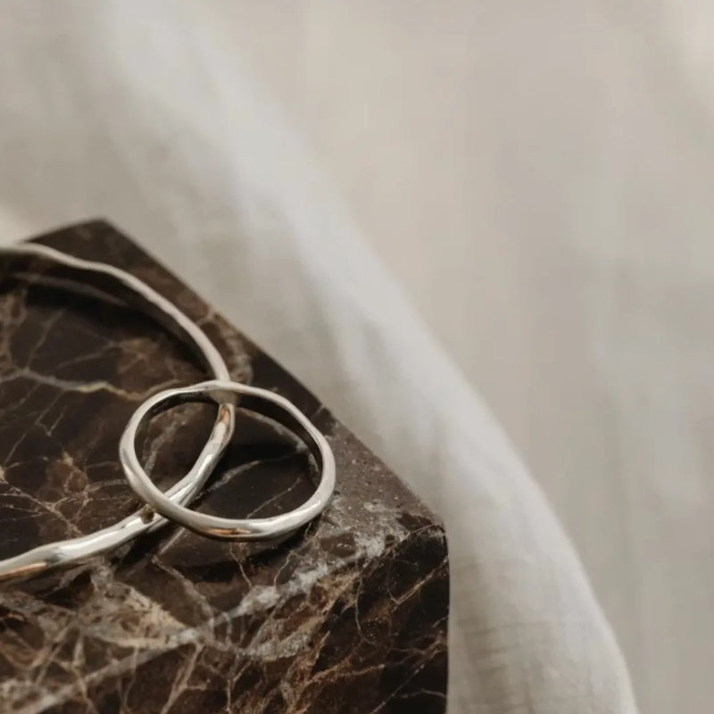 bague et jonc argent sur un support en marbre marron