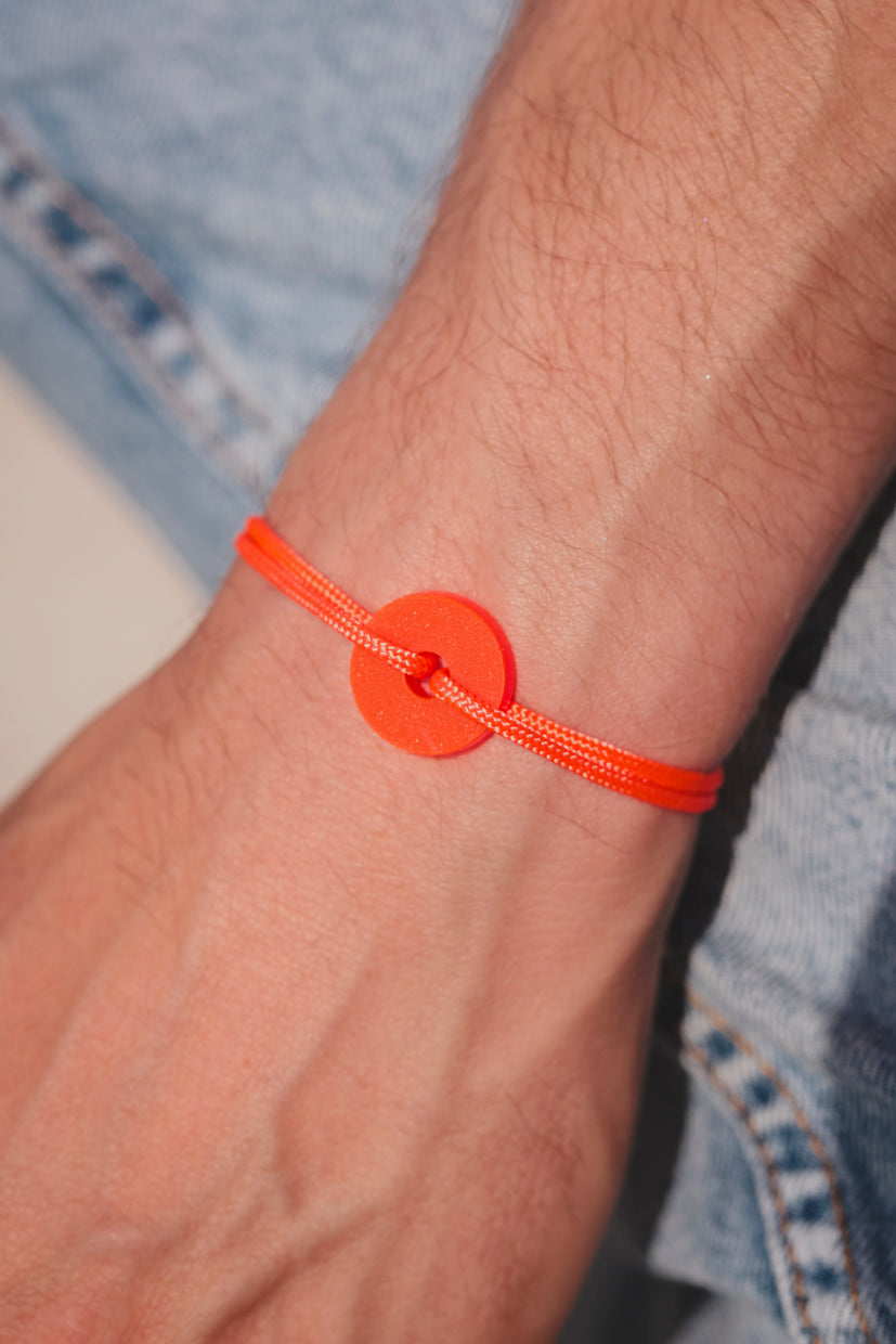Bracelet La Cible Pop en acétate fluo orange, pastille ronde sur poignet