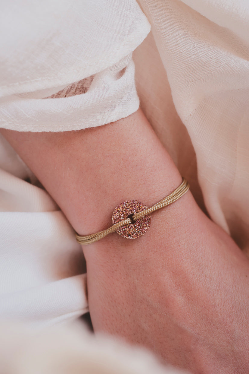 Bracelet doré à perles tressées et pendentif scintillant sur le poignet