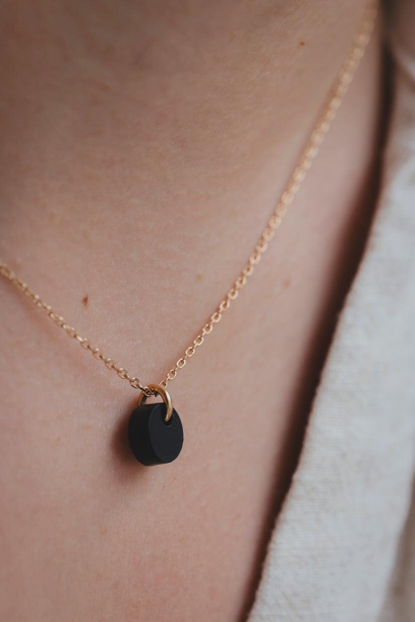 Collier chaîne dorée avec pendentif galet noir lisse