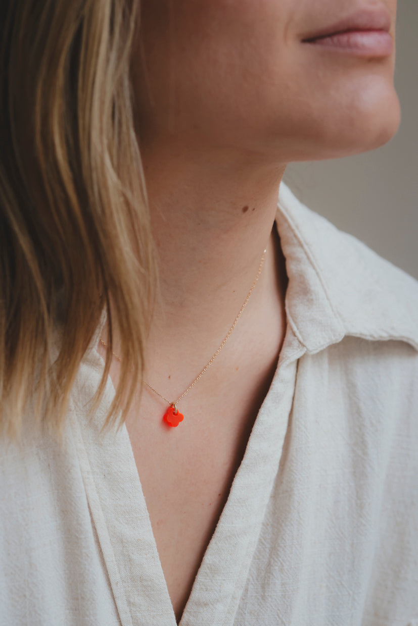 Collier doré pendentif trèfle orange, porté sur chemise