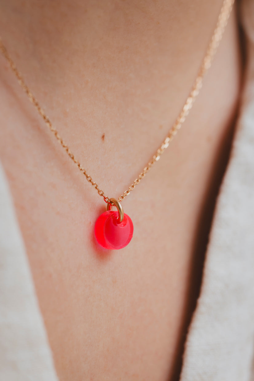 Collier à chaîne dorée avec pendentif galet rouge lumineux