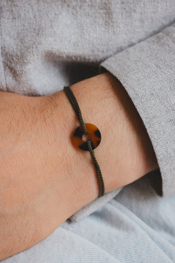 Bracelet paracorde noir et pendentif écaille orange en forme de cible sur poignet