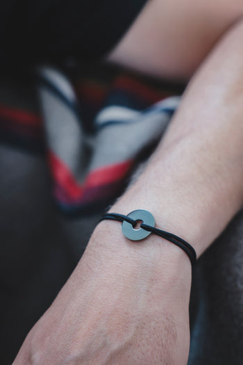 Bracelet La Cible argent 925 rhodié, pastille ronde et cordon foncé au poignet.
