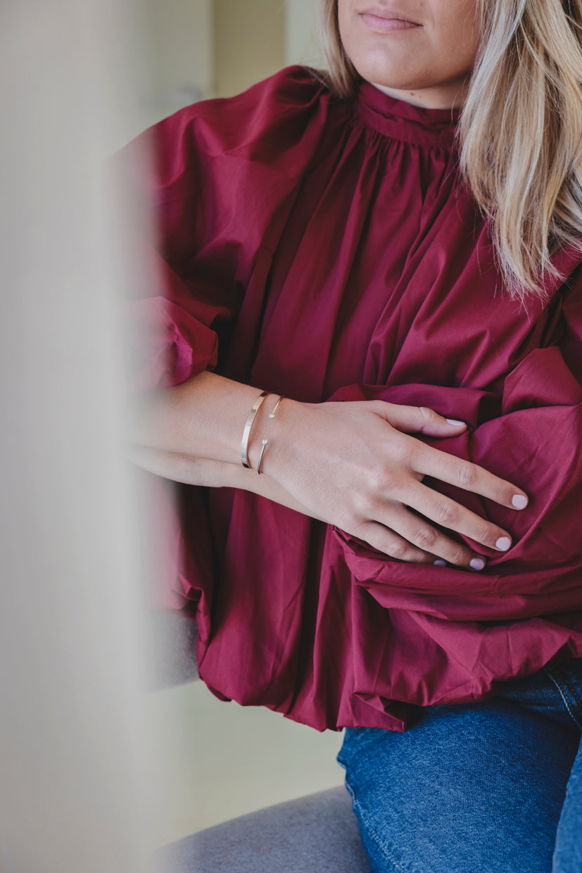 Bracelet jonc argenté à deux perles, porté avec une blouse bordeaux