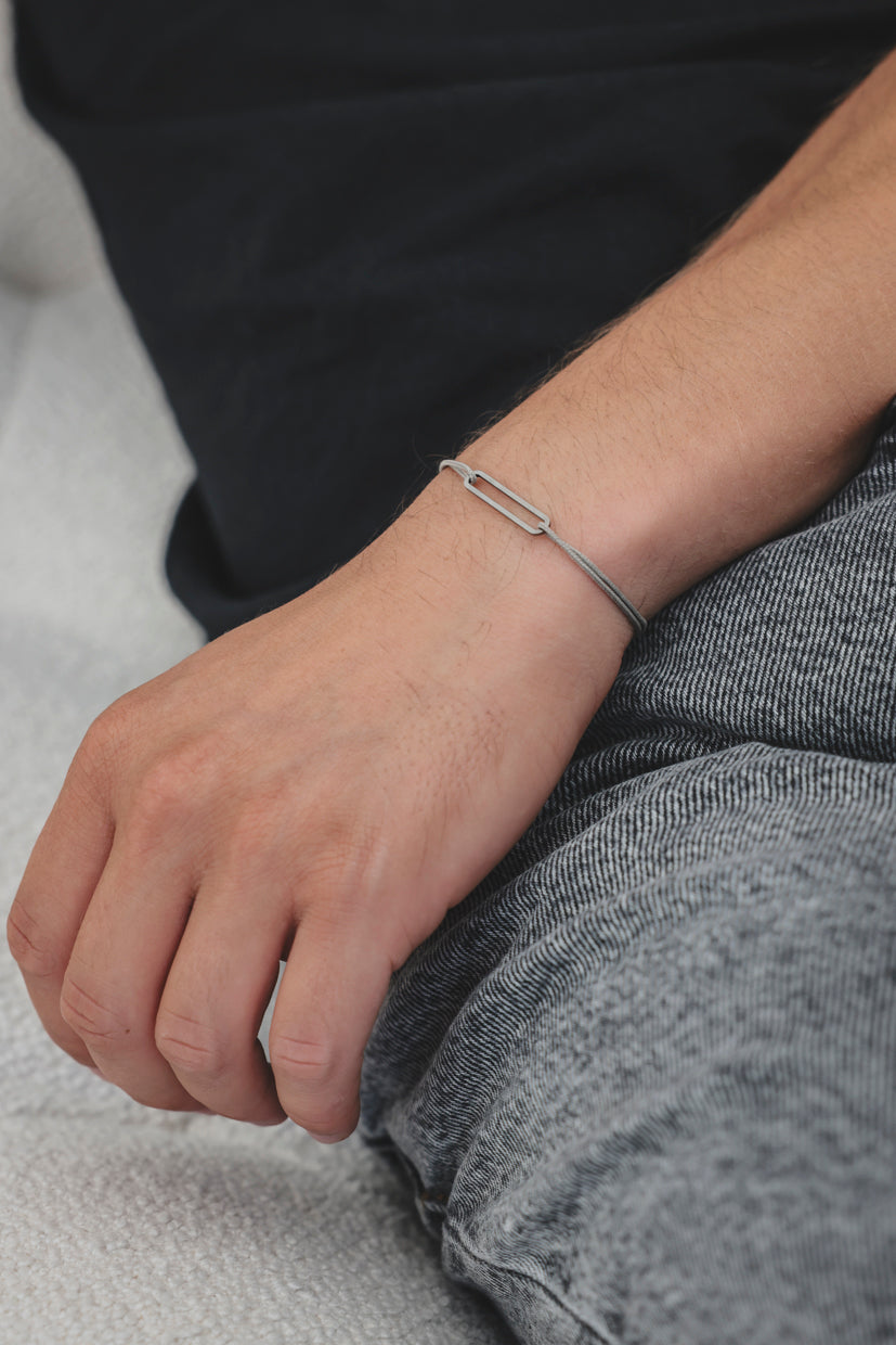 Bracelet argent 925 rhodié à maillons rectangulaires sur cordon noir, porté à la main
