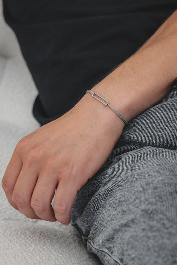 Bracelet argent 925 rhodié à maillons rectangulaires sur cordon noir, porté à la main
