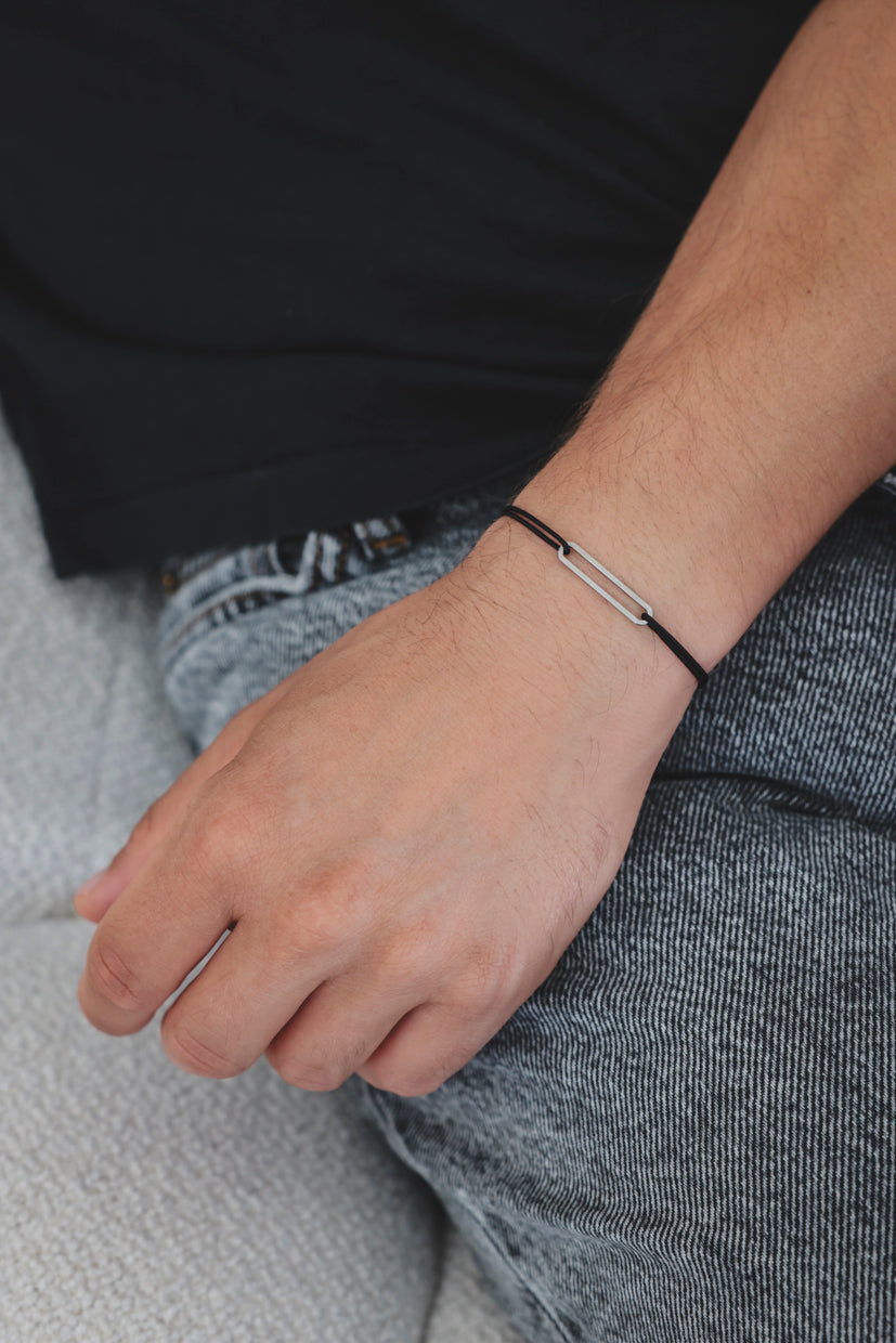 Bracelet argent 925 rhodié avec maillons rectangulaires sur cordon noir, porté au poignet