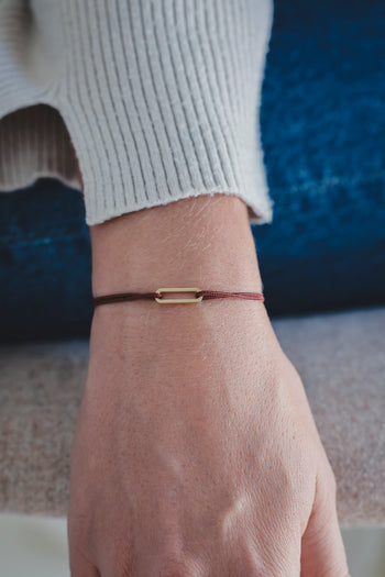 Bracelet Le Petit Maillon à plaque or, cordon noir sur poignet