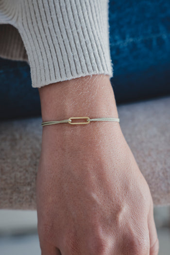 Bracelet Le Petit Maillon à plaque or sur poignet, paracorde beige