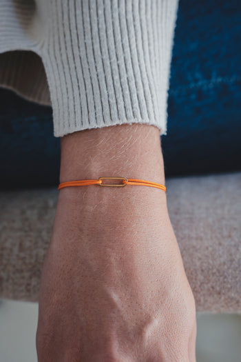 Bracelet Le Petit Maillon à plaque or sur poignet, paracorde orange