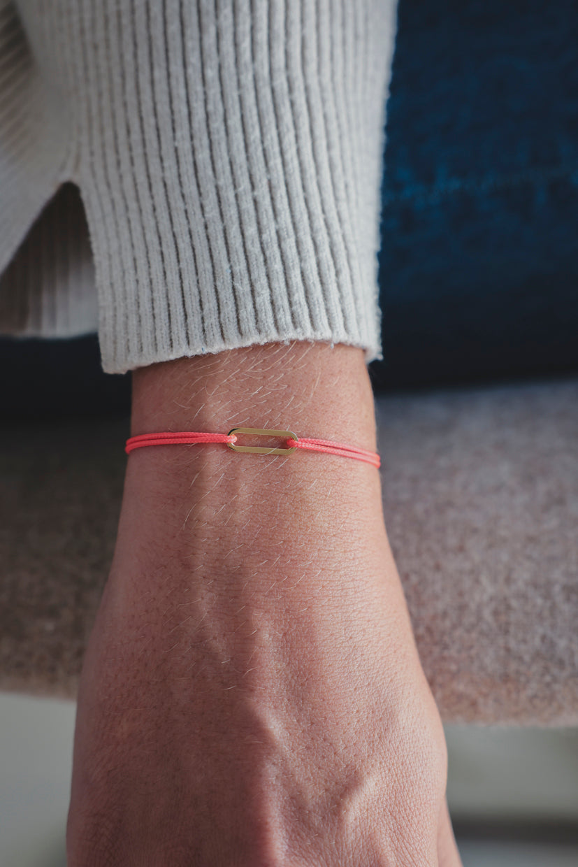 Bracelet Le Petit Maillon à plaque or sur poignet, paracorde rouge