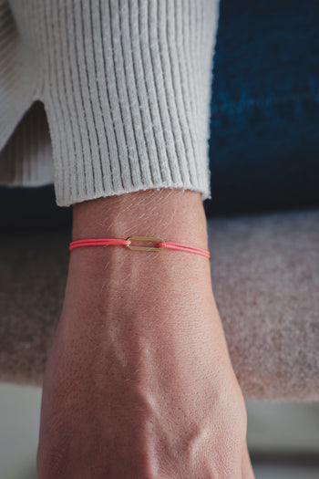 Bracelet Le Petit Maillon à plaque or sur poignet, paracorde rouge