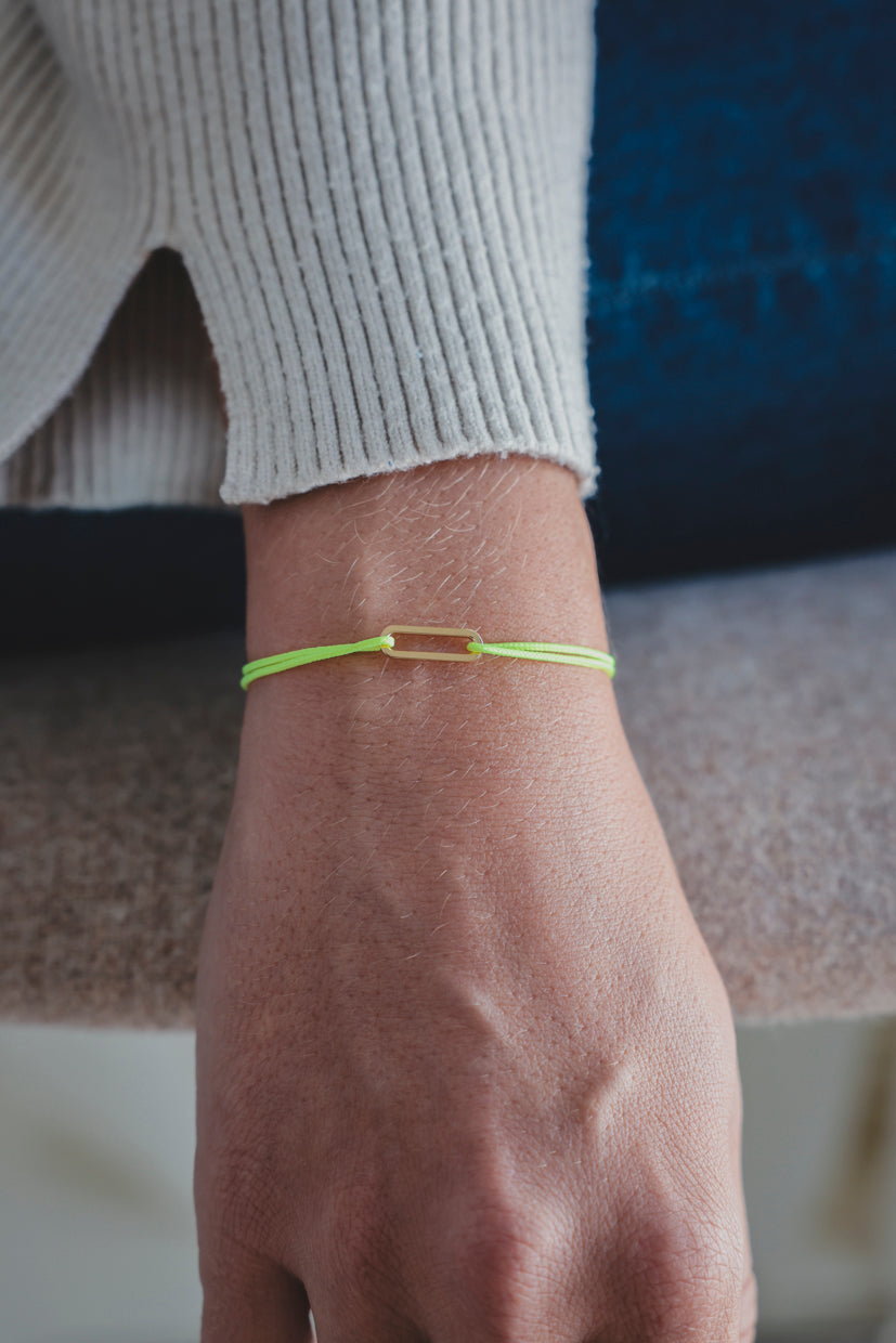 Bracelet Le Petit Maillon à plaque or sur poignet, paracorde vert