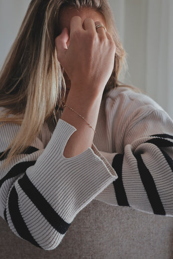 Bracelet chaîne dorée sur poignet, porté avec pull à manches longues