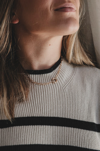 Collier chaîne dorée porté près du cou, maillons fins et pendentif