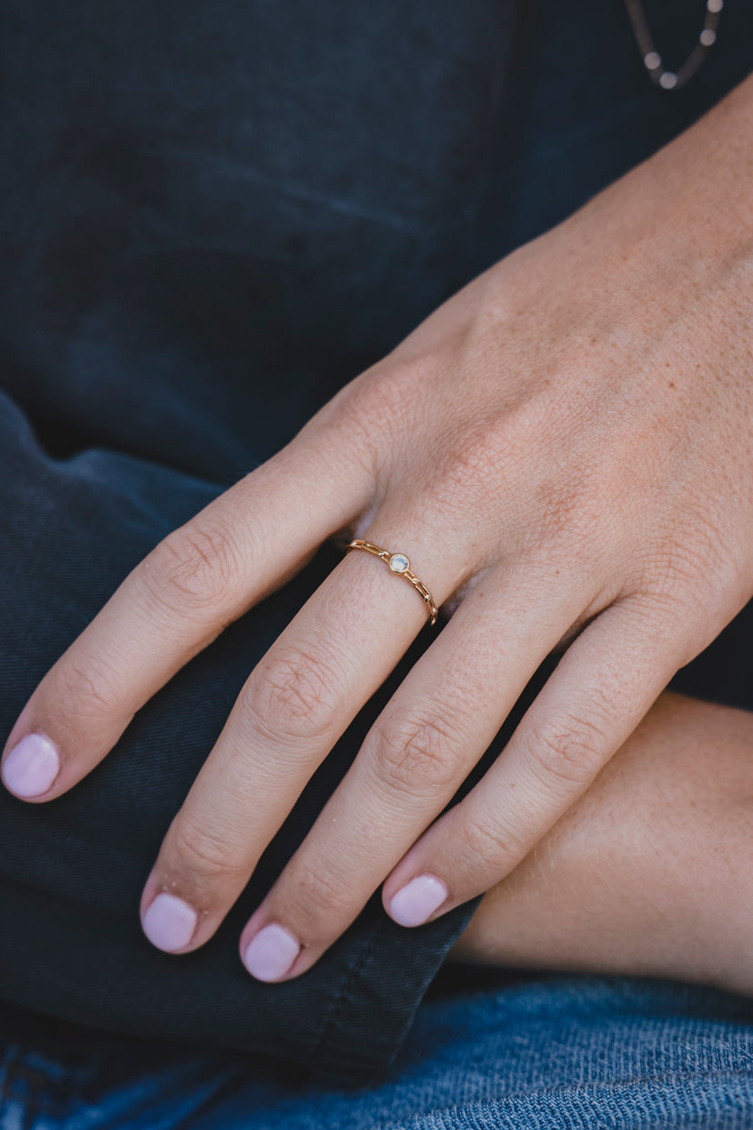Bague dorée avec petite pierre sertie, portée sur l’annulaire