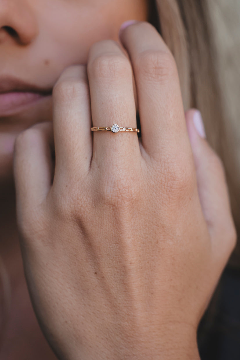 Bague dorée à pierre centrale, vue rapprochée sur l’index