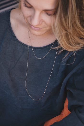 Collier sautoir fin en métal doré, chaînettes longues superposées sur le buste