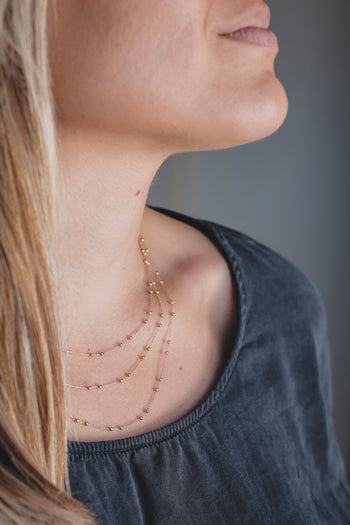 Collier sautoir doré avec petites perles, aperçu sur la nuque