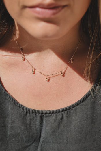 Collier Sonora gros plan : chaîne dorée, pendentifs goutte et pierres rouges
