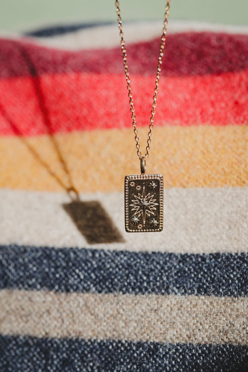 Collier Solia : pendentif rectangulaire à motif étoile doré, chaîne fine en métal.