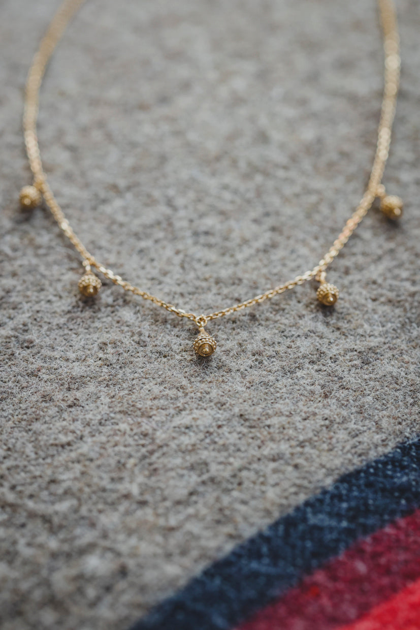 Collier Sonora chaîne dorée avec petits pendentifs et pierres rouges, vue de face