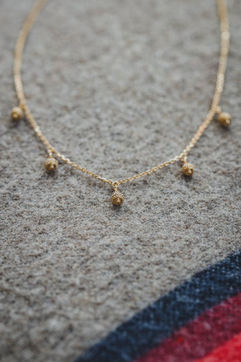 Collier Sonora chaîne dorée avec petits pendentifs et pierres rouges, vue de face